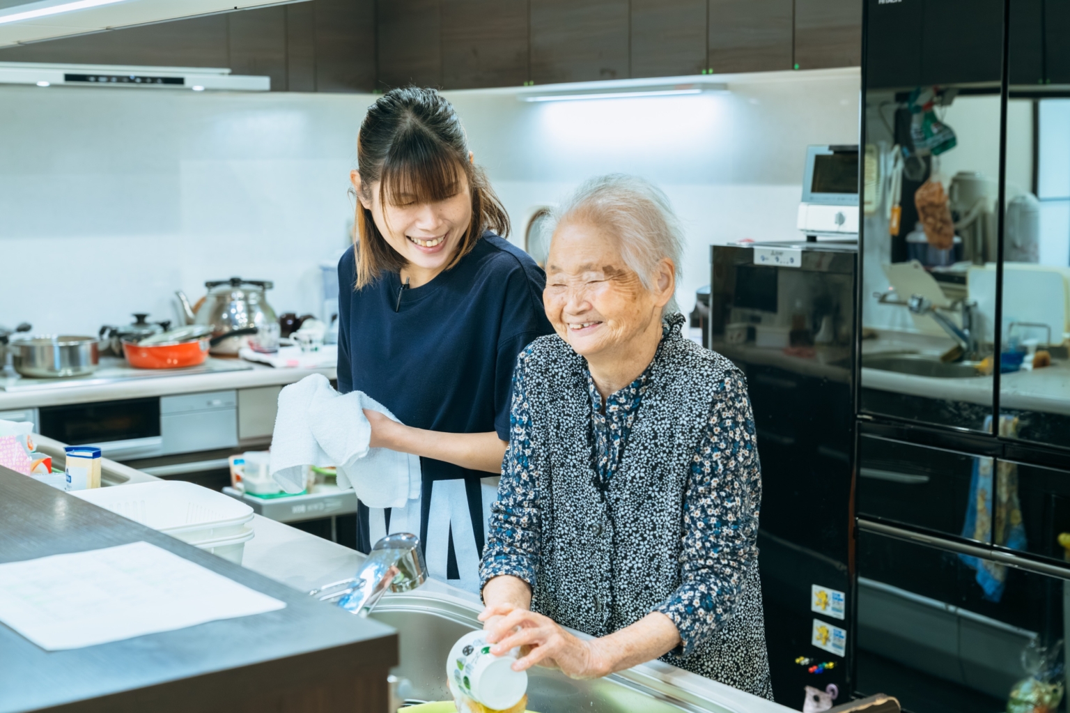 スタッフと入居者が厨房で一緒に調理や食事準備をしている様子